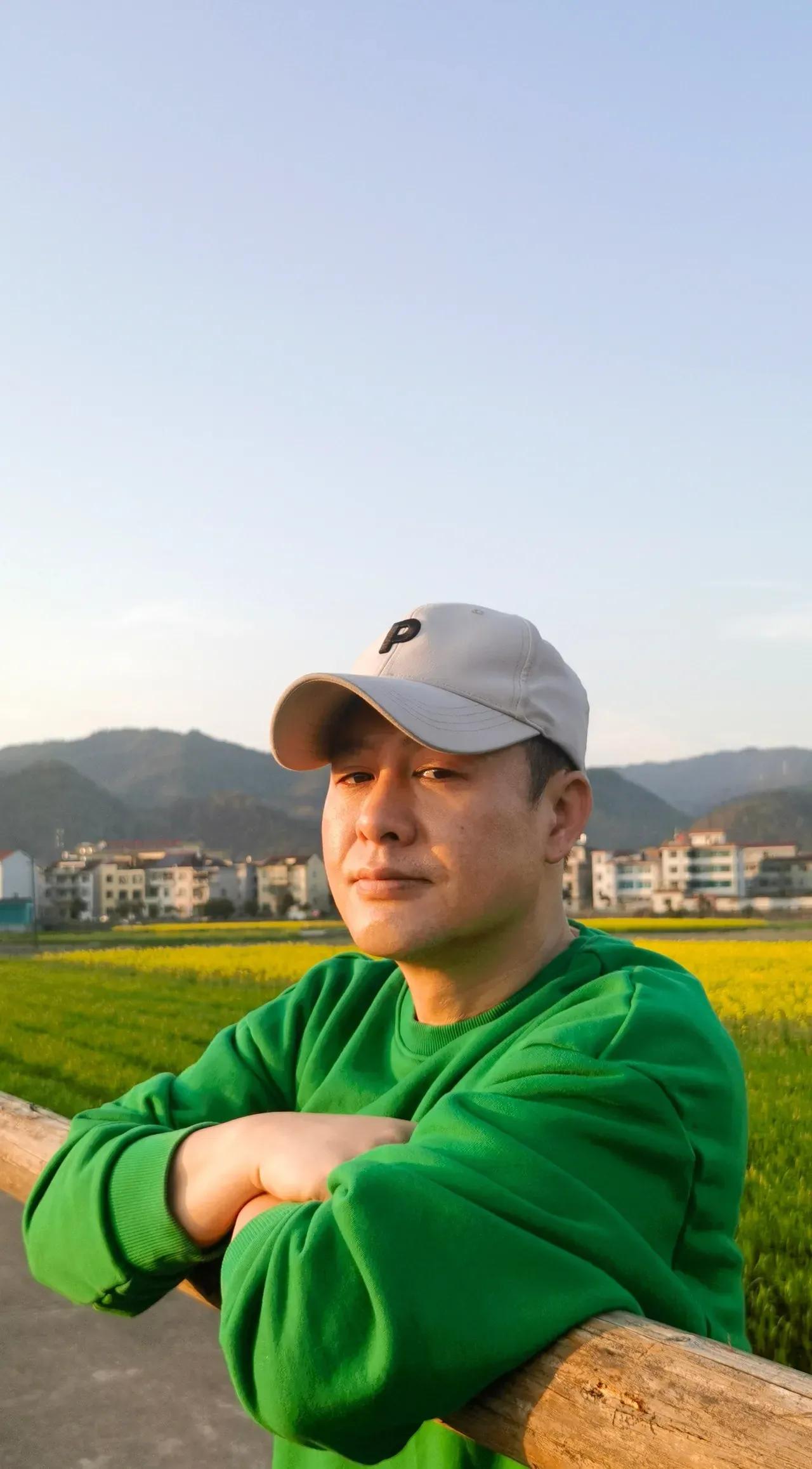 张颂文田间地头低调与人热恋，穿绿色卫衣，戴着米色棒球帽，打扮得阳光时尚又减龄，看