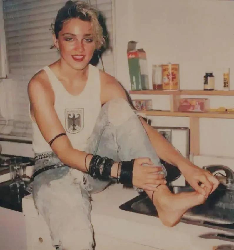 1982年的美国纽约,坐在炉灶上抠脚丫子的麦当娜。当时麦当娜青春时尚、放荡不羁,