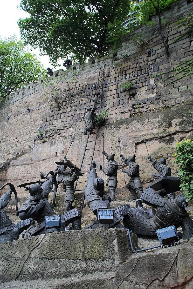 “太假了！”一组古代士兵攻城瞬间的雕塑。一人正沿着梯子向上攀登，地下站立几名长矛
