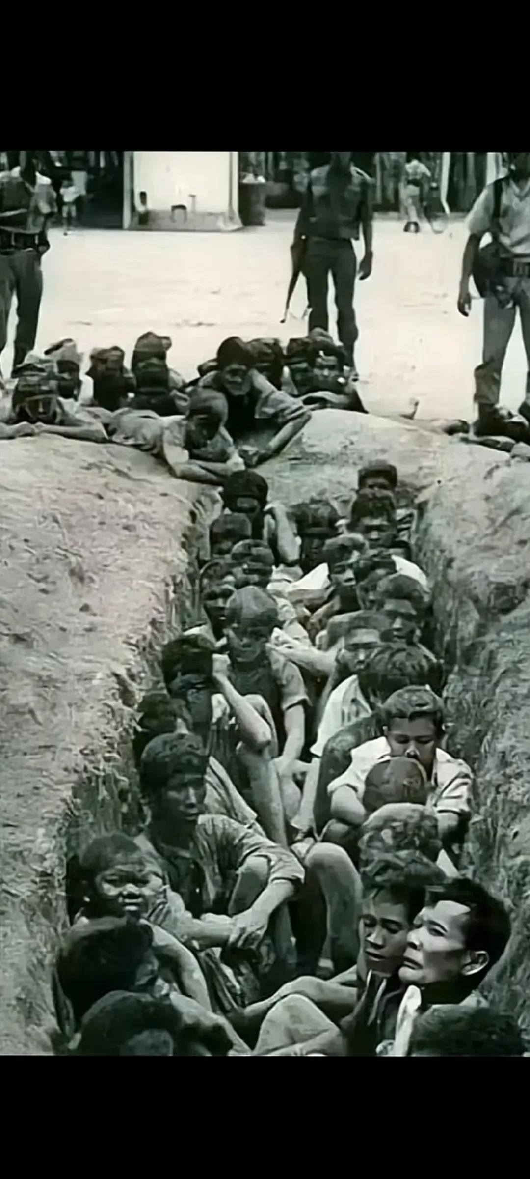 1965年一堆华人坐在土坑里等待被活埋，他们放弃了抵抗垂头丧气，满脸绝望等待着死