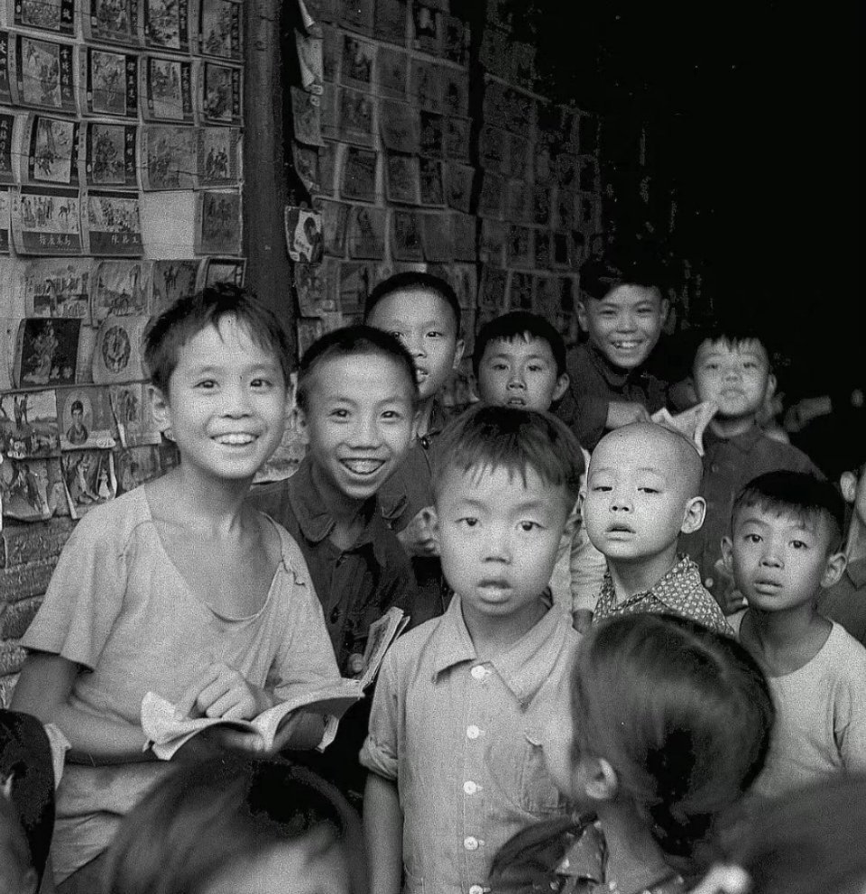 1959年的成都。上个世纪，一个胡同里的书摊被孩子们围得水泄不通。摊位的墙上贴满