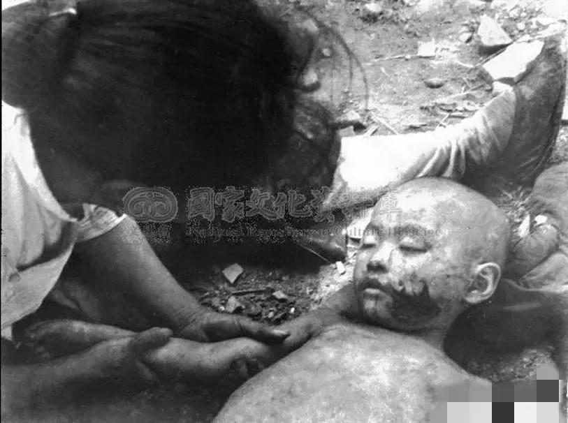这是1938年，武汉街头，一名被日本飞机炸死的小男孩。照片中的他躺在地上，已经失