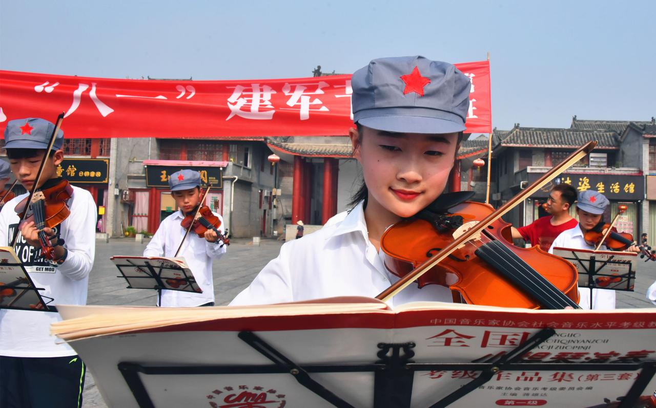 为迎接建军90周年，7月26日，社旗县赊店古镇文化广场上空琴声悠扬，数十名戴着红