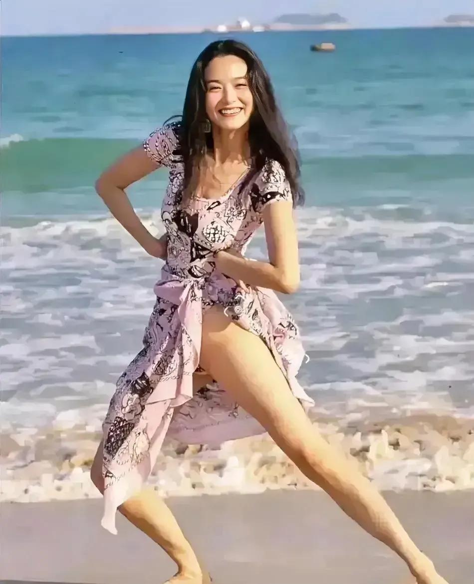 网友分享林青霞年轻时候的海边照片，当时林青霞穿着碎花长裙，光着脚在沙滩上玩耍，看