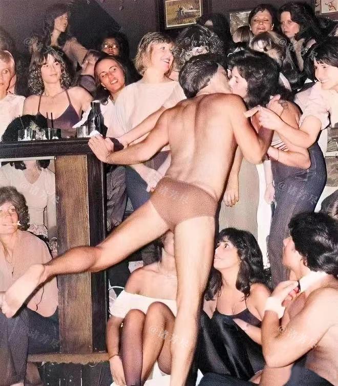 1970年，美国，一名脱衣舞男正在和台下的女观众热吻，镜头中的他只穿了一件三角裤
