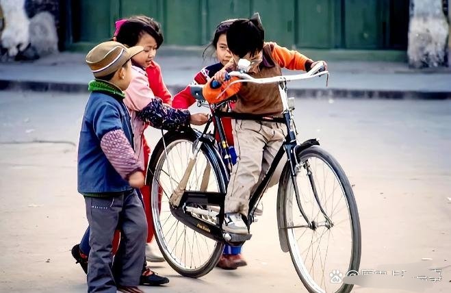 #历史那些事[超话]#80年代阳朔街头骑自行车的孩子，这应该是凤凰牌的二八大杠，