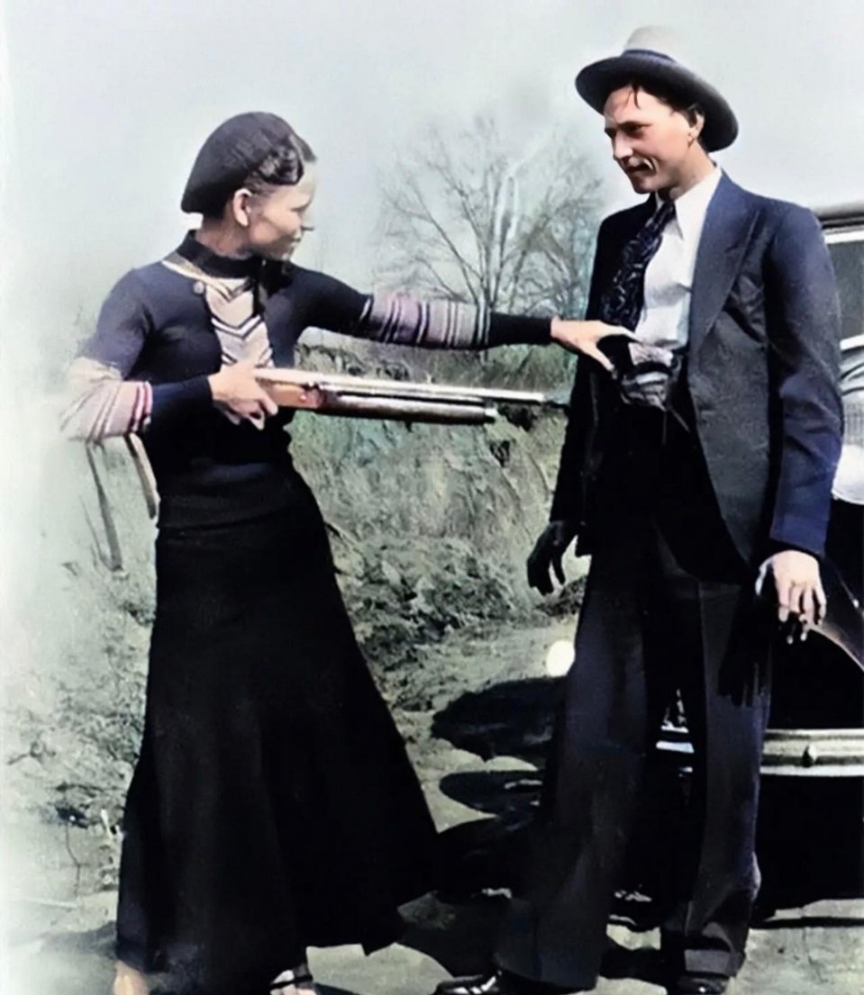 #历史那些事[超话]#女人一手持枪指着男的肚子。男人拿着一支烟，很平静。两者不是