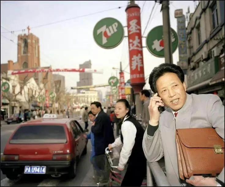 上世纪90年代初，上海街头，一个男人正拿着手机在打电话。
这个男人西装革履，手夹
