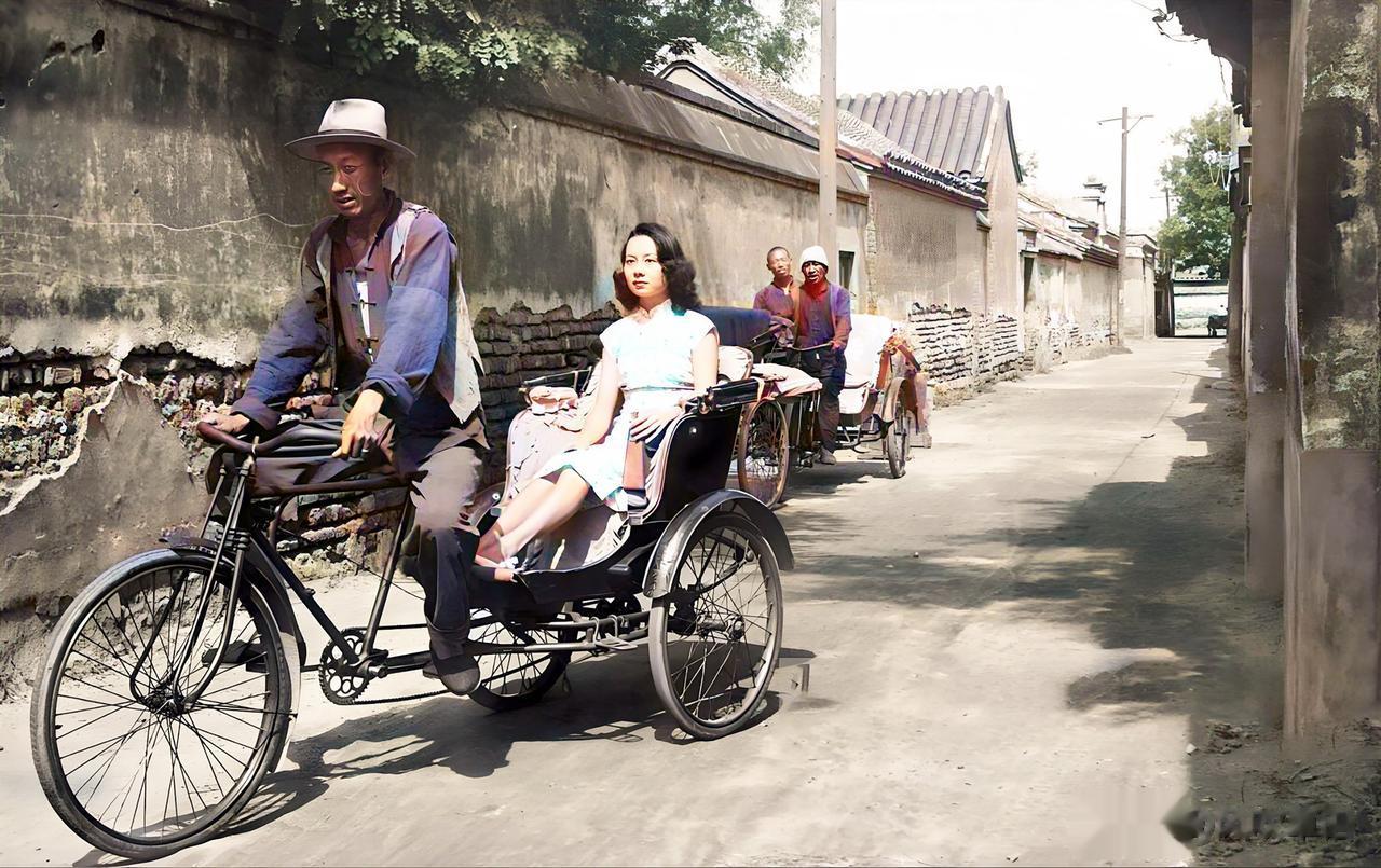民国时期，一名妙龄女子坐着人力车穿行在胡同里。姑娘烫着大波浪，穿着时尚的旗袍，手