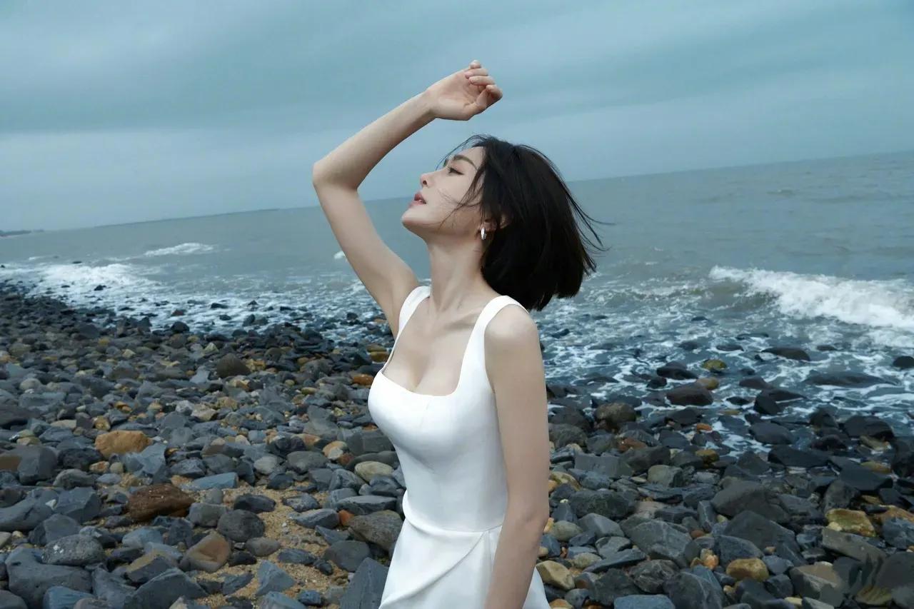 秦岚海边摆拍造型清新靓丽，清纯唯美！

穿白色低胸高开叉长裙，低胸背心裙，秀出诱