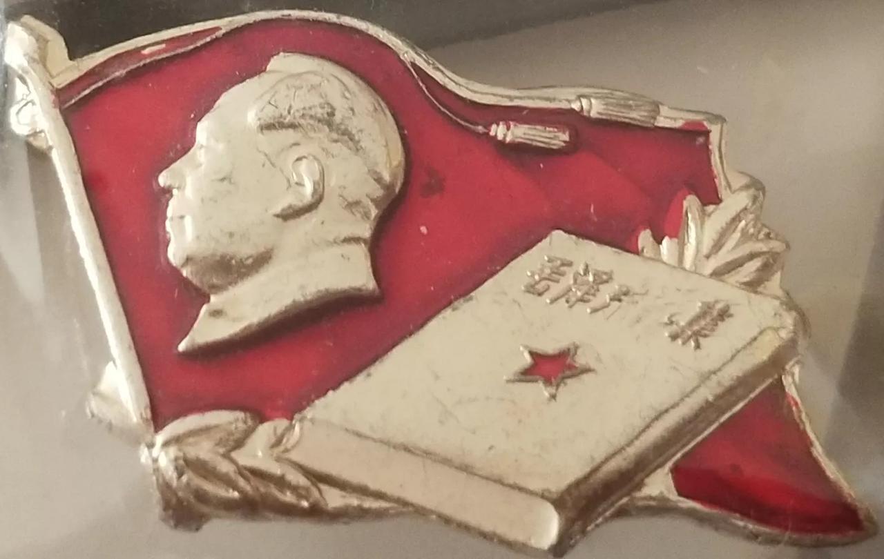 毛选书籍纪念像章
该像章是一枚以红色和金黄色为主，采用铅铝合金制作而成的旗状小型