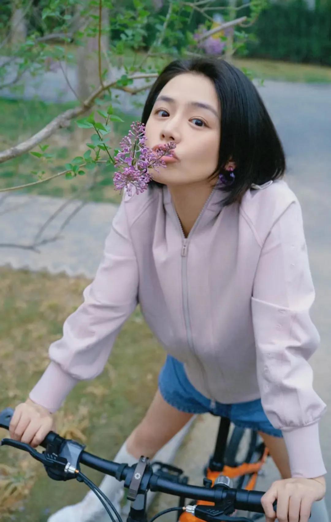 马思纯分享骑车随拍，骑行中时而闻着花香，时而俏皮的双腿叉开，时而停下来看着镜头等