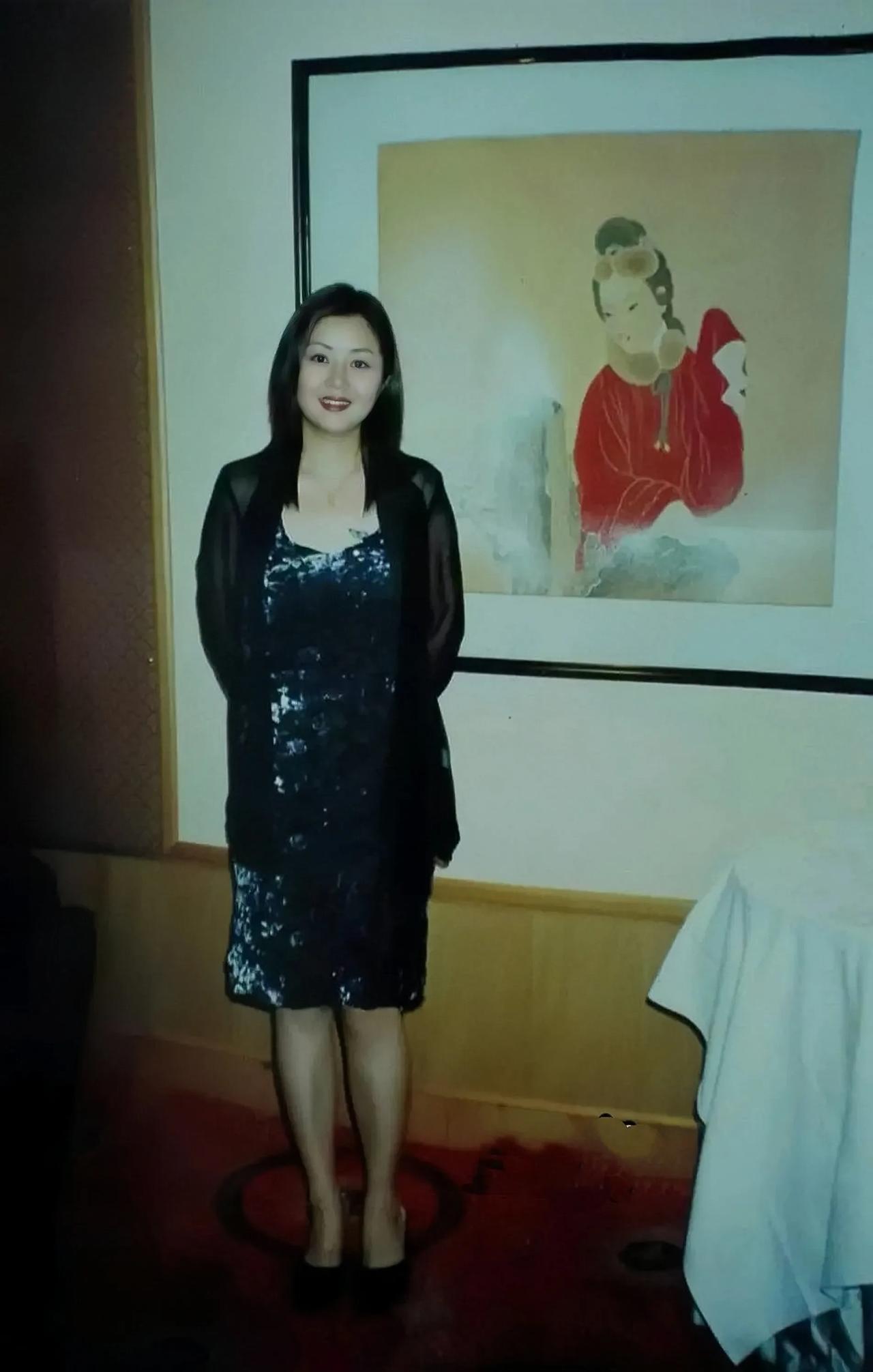 20多年前，一个妩媚迷人的美妇站在一张古代仕女图前的留影。
这个美女身材丰腴，珠