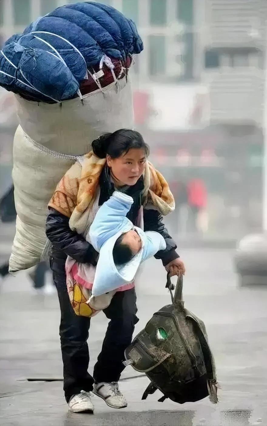 江西南昌火车站，一位母亲背着超大行李，抱着着襁褓中的孩子，缓慢地向着出站口走去。