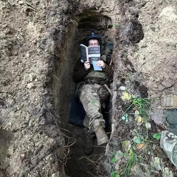 这是无人机拍摄的视频：有一乌军士兵躺在战壕里看书，这气场真强大，心态也好，还有心
