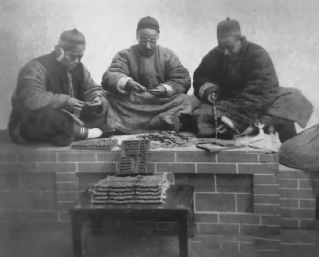 清末时期真正的土豪，坐在火炕上数钱数到手抽筋。
照片中的三个“土豪”正坐在一张火