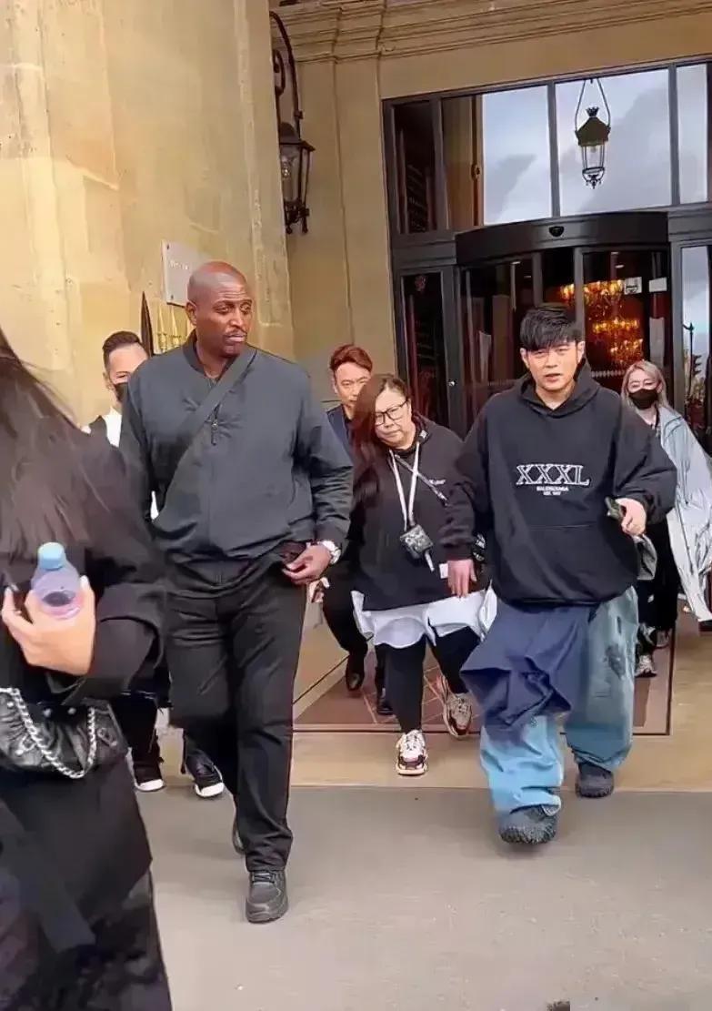 周杰伦出行时的场景，前呼后拥，身边有黑人保镖跟随，因为装扮太丑，几乎认不出是他。
