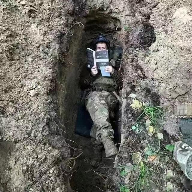 一名年轻的乌克兰士兵躺在战壕里读书，一架俄军无人机记录下了这个珍贵画面。镜头中的
