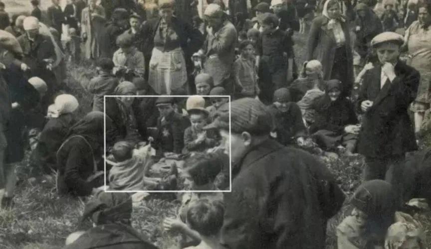【图一】1944年5月，一个孩子在到达奥斯威辛后不久给坐在对面的小男孩送花（白框