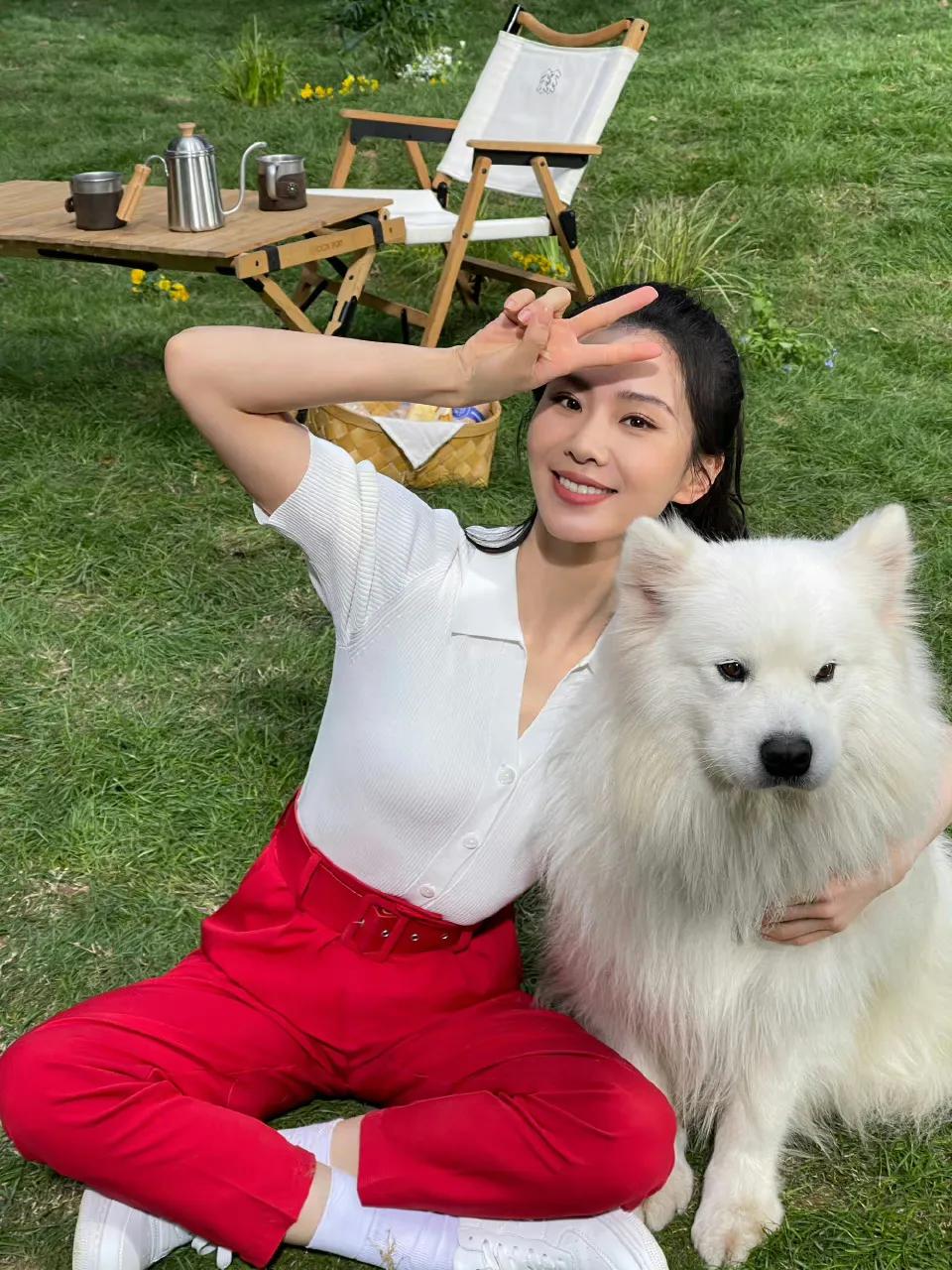 刘诗诗白色短袖上衣搭配红色长裤，简约、明亮，和小狗在草地上玩耍看着好有爱。