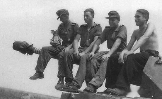 德军一辆四号坦克的乘员坐在炮管上合影留念，左边的车长还抱着一只吉祥物。注意画在炮