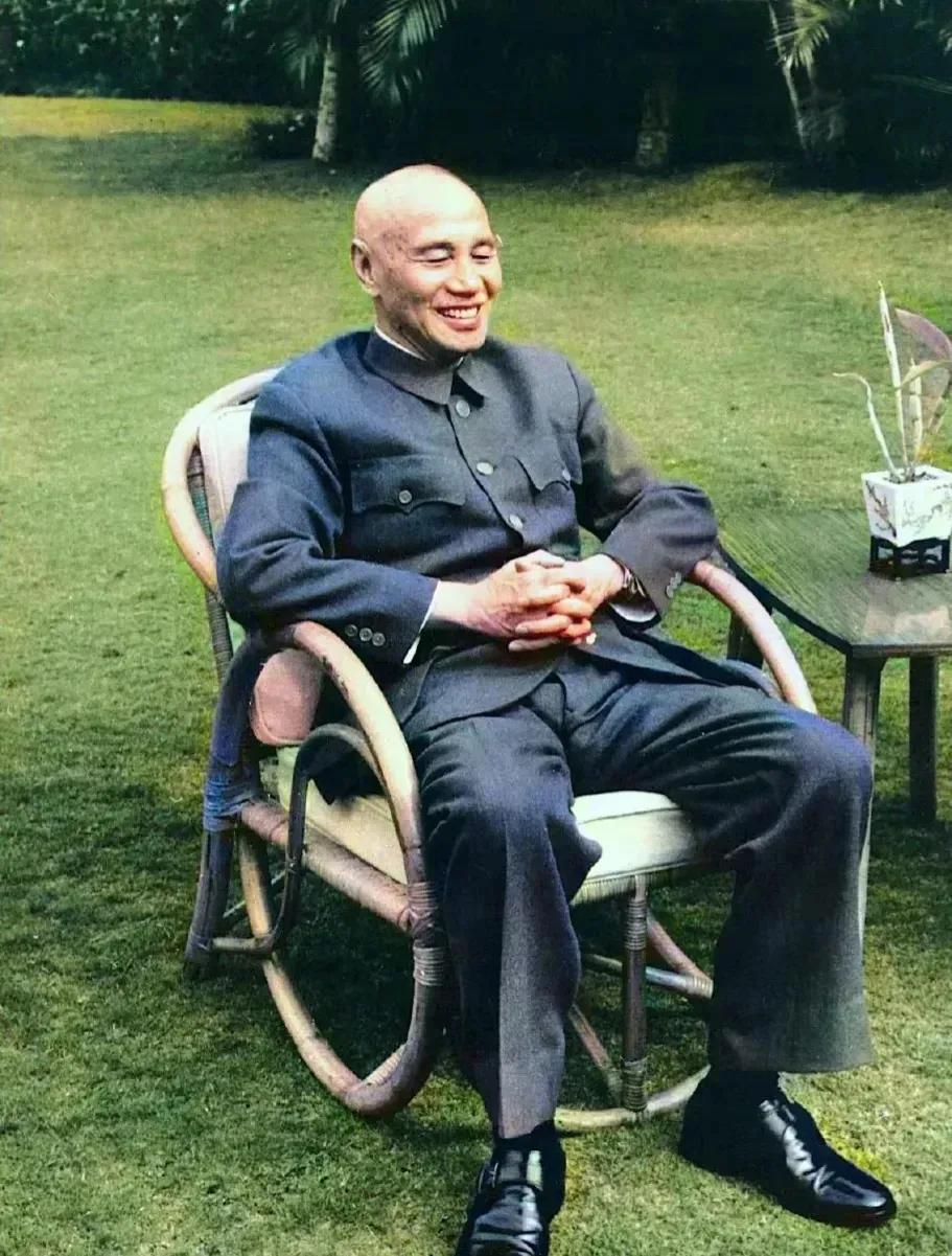 1964年台湾。草坪上一位老人正坐在一张藤椅上，双手食指紧扣，略显拘谨。从面相上