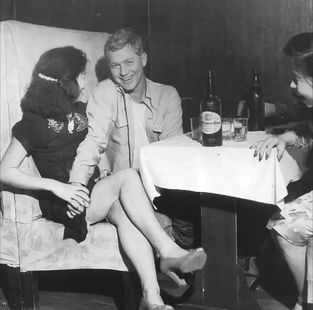 1947年的上海舞厅，一个美国大兵和两个身着旗袍的舞女正在饮酒作乐，三个人举止轻