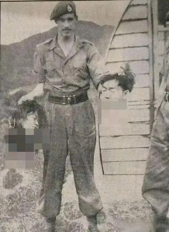 这是1969年，发生的马来西亚5.13事件，一名警察双手各提着一颗华人夫妇的人头